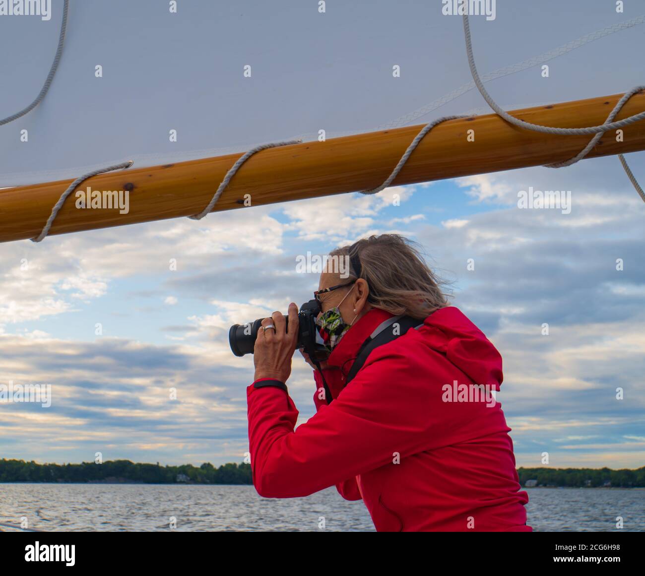 Ältere Fotografin, die von einem historischen Segelboot fotografiert Stockfoto