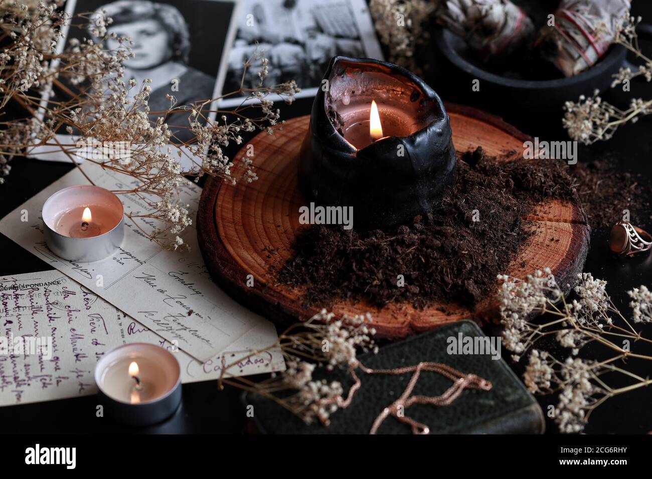 Spell Casting auf Samhain (Halloween), um Geister von toten Verwandten zu kontaktieren. Dunkler und geheimnisvoller Hexenaltar mit alten Postkarten-Fotos Stockfoto