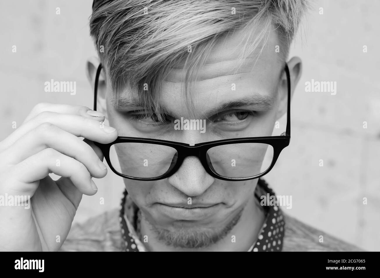 Blonde Mann mit kleinem Bart zieht seine Brille in Überraschung.Junge Mann mit lustigen Haarschnitt in der Brille Grimasse machen - lustige Gesicht. Emotionen und si Stockfoto