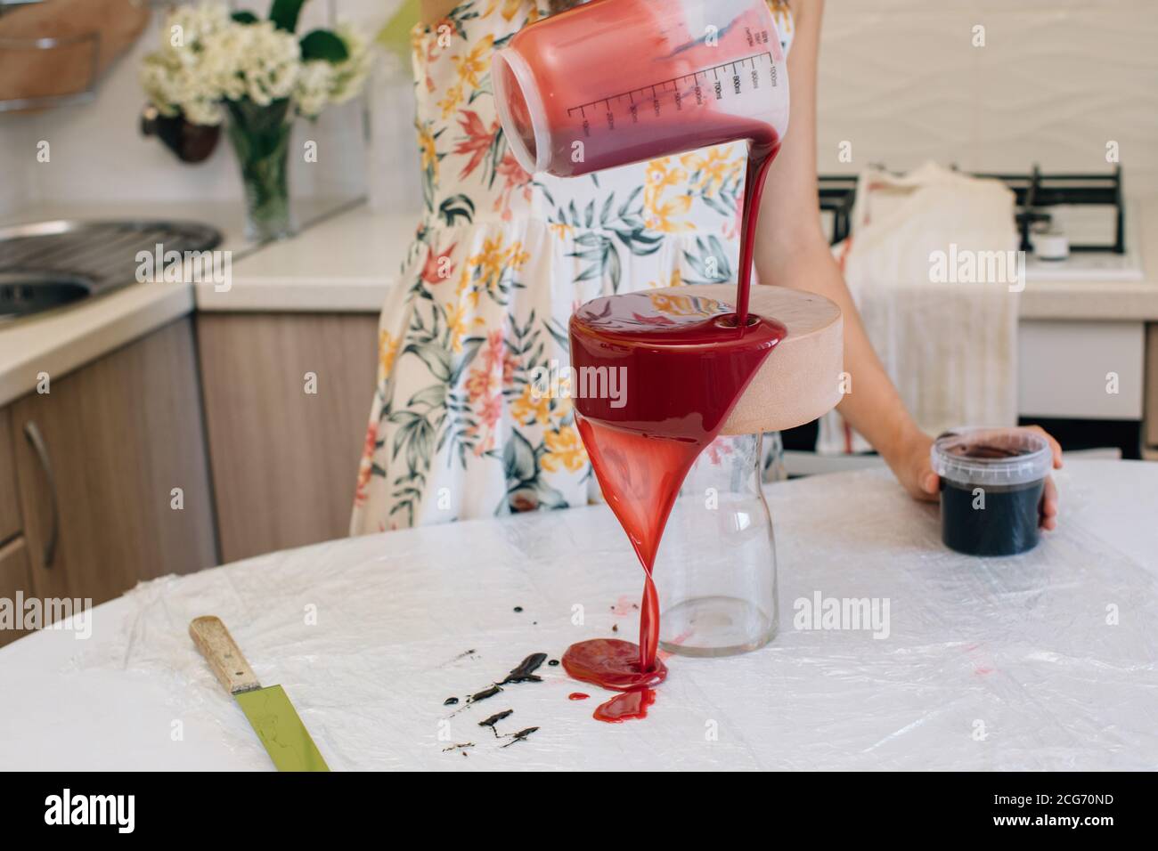 Frau Gießen Glasur über eine hausgemachte rote Samt Schokolade Kuchen Stockfoto
