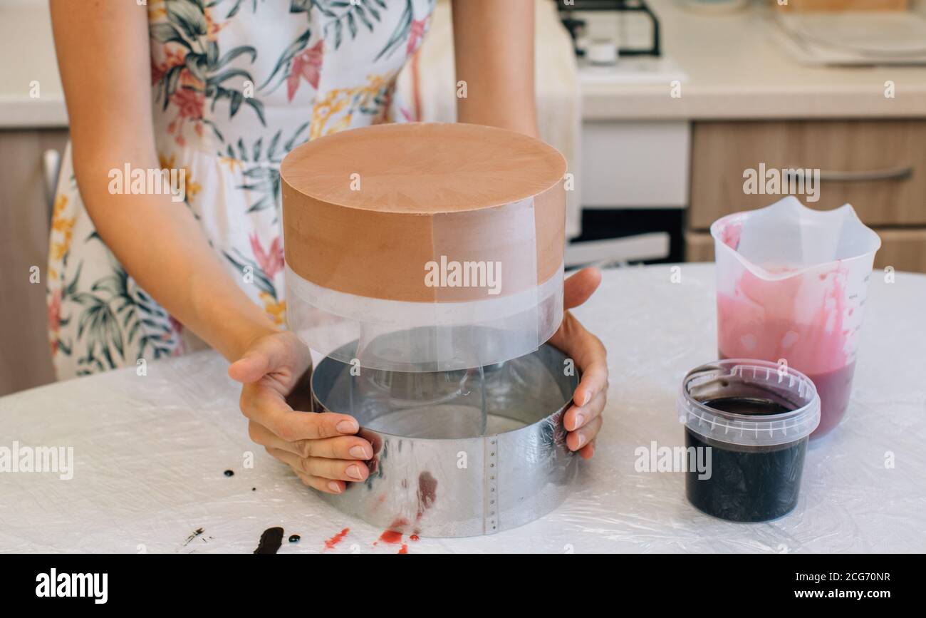 Frau, die einen roten Samt-Schokoladenkuchen aus einem Backen entfernt Zinn Stockfoto