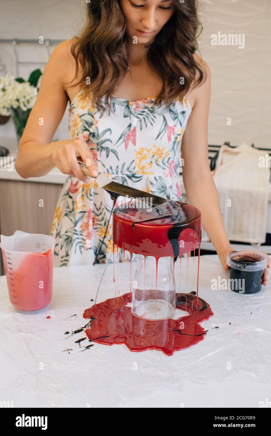 Frau glasieren einen selbstgemachten roten Samt-Schokoladenkuchen Stockfoto