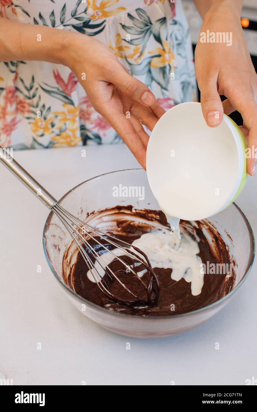 Frau Zugabe von Milch zu Schokoladenkuchen Mischung Stockfoto