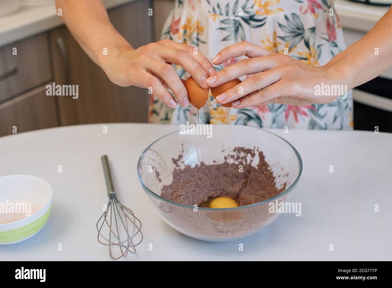 Frau, die Eier zu einer Schokoladenkuchenmischung hinzufügt Stockfoto