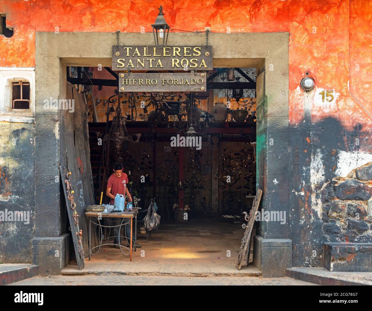 Fassade einer schmiedeeisernen Werkstatt mit einem jungen Mann bei der Arbeit, Antigua, Guatemala. Stockfoto