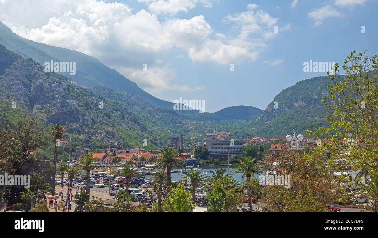 Top Luftbild mit Blick auf die Boka Bucht und Palmenpromenade mit Touristen, Autos und Boote im Herzen der Stadt Kotor in Montenegro an einem sonnigen Tag Stockfoto