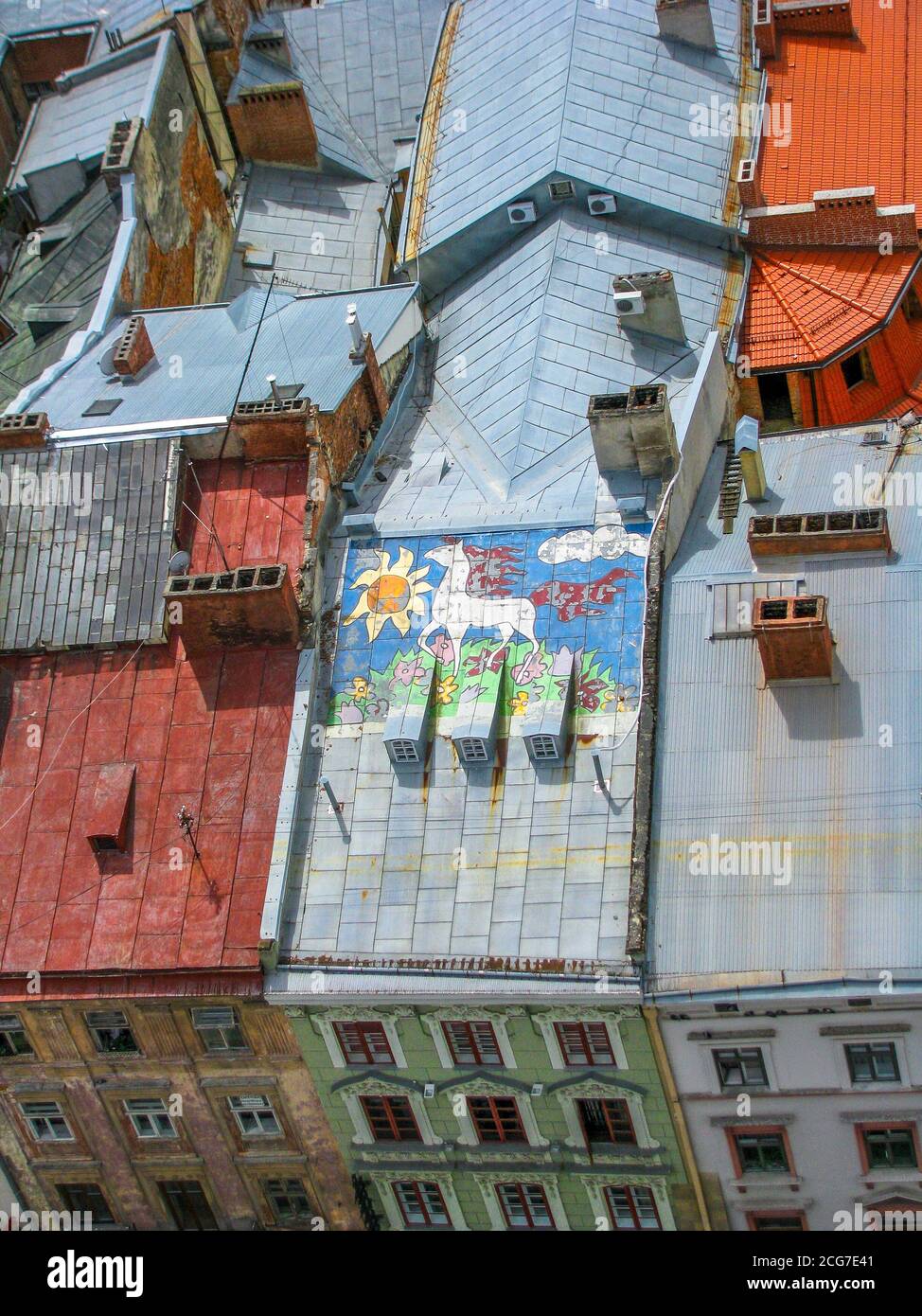 Luftaufnahme über die gefliesten und mit Stahl bedeckten Dächer von alten Gebäuden mit Pferd Graffiti Kunstwerk auf einem, Lviv Stadt, Ukraine. Stockfoto