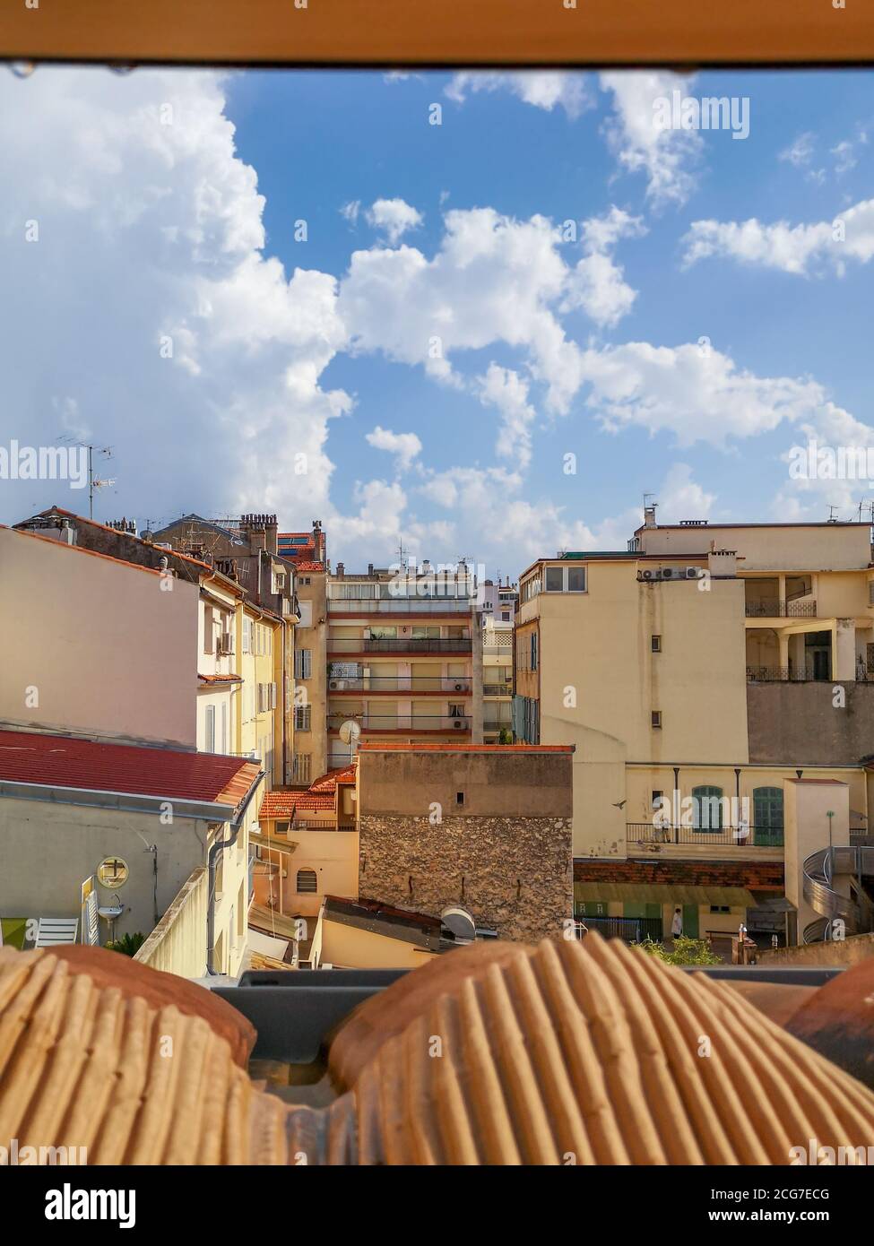 Blick vom roten Ziegeldach über geschlossenen gemütlichen Hof umgeben von Schulgebäude und alten traditionellen Häusern in sandigen Farben mit Terrassen und Balkonen. Stockfoto