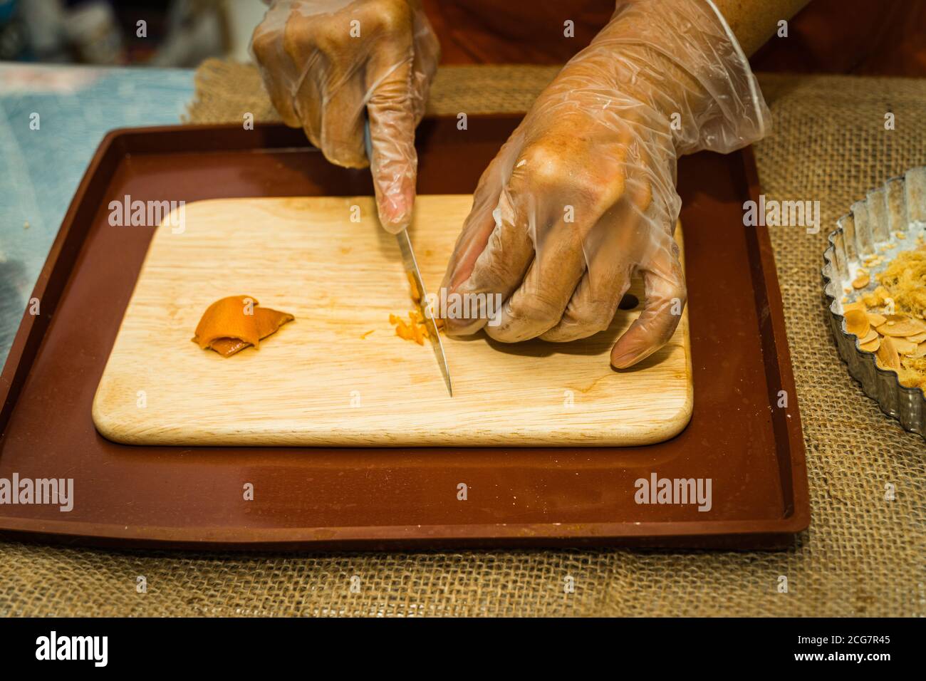 Eine Nahaufnahme der Hand einer Frau mit einem Messer geschnitten getrocknete Mandarine Schale auf einem hölzernen Schneidebrett. Food-Konzept Stockfoto