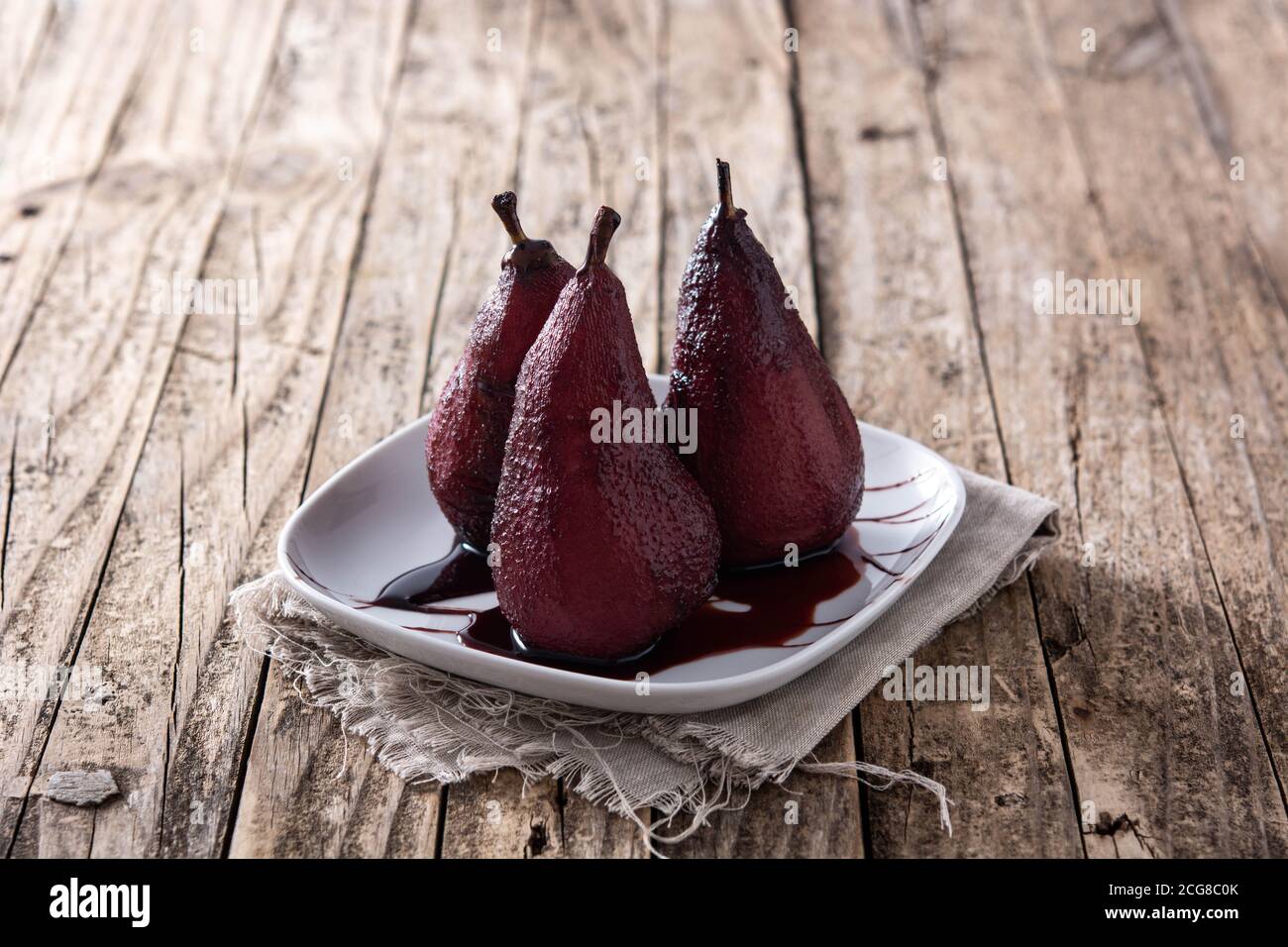 Pochierte Birnen in Rotwein auf Holztisch Stockfoto