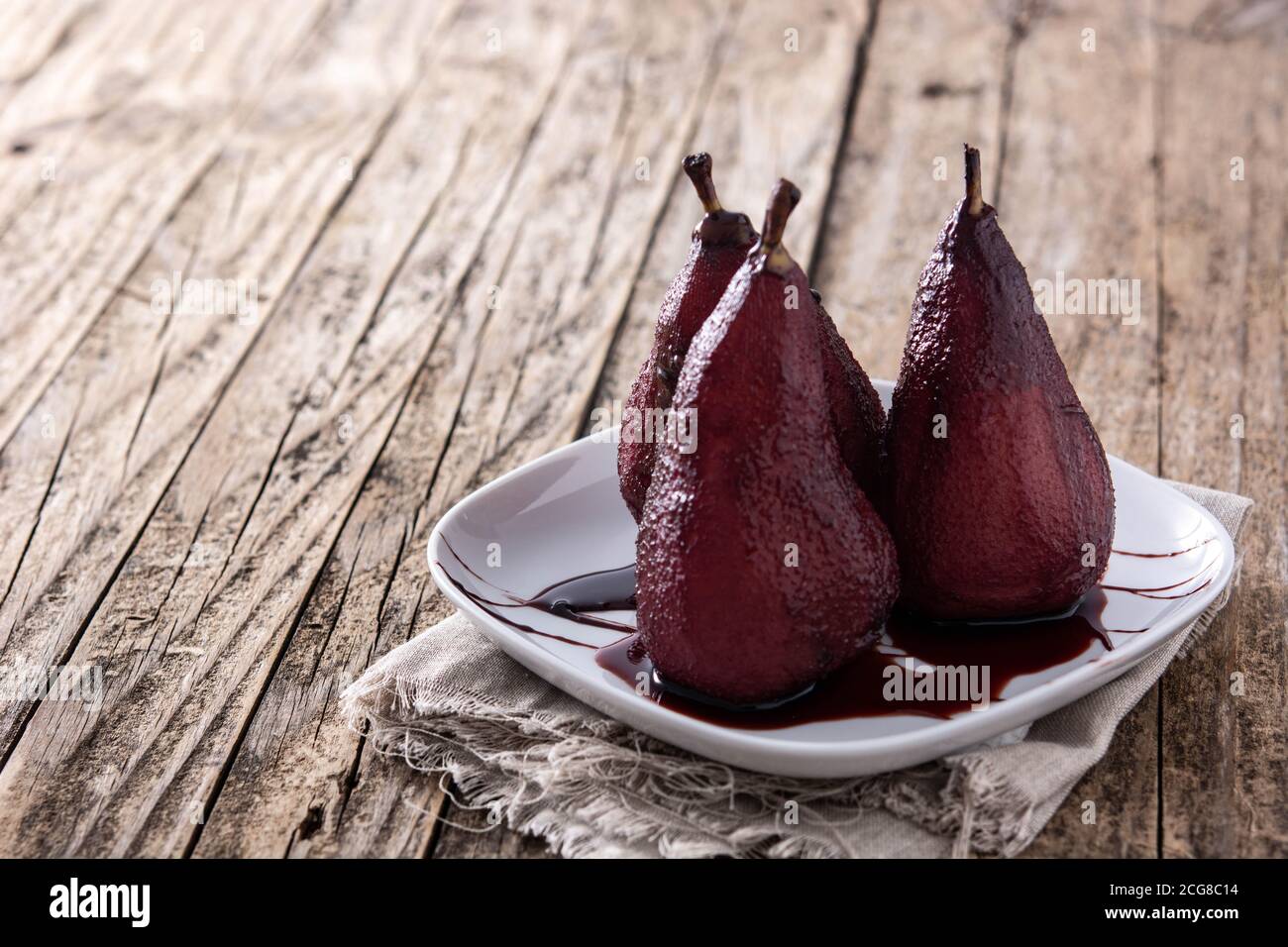 Pochierte Birnen in Rotwein auf Holztisch.Platz kopieren Stockfoto