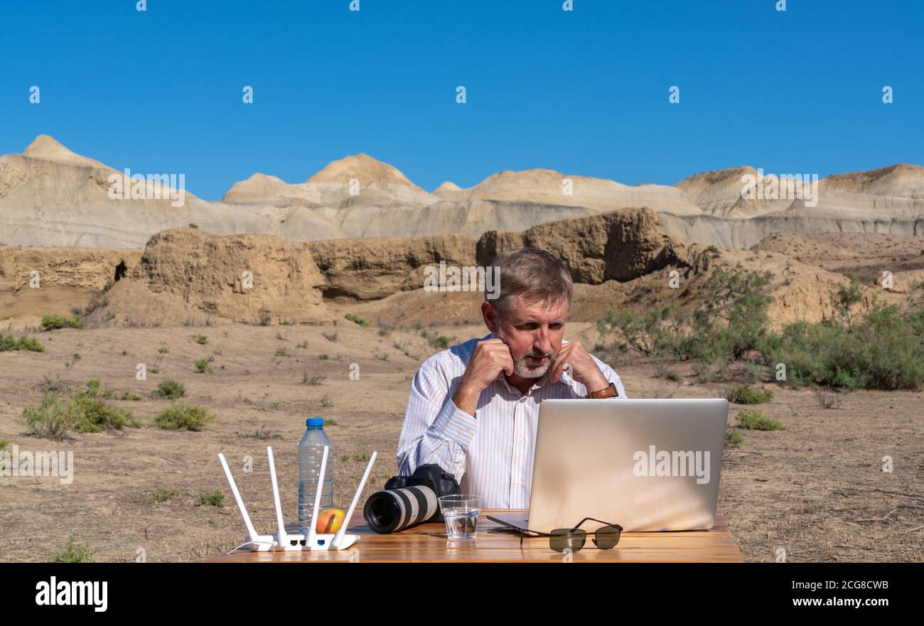 Fotograf arbeitet am Tisch im Freien auf dem Laptop Stockfoto