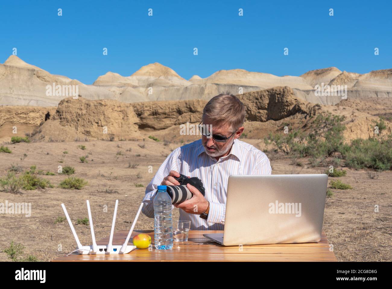 Fotograf arbeitet am Tisch im Freien auf dem Laptop Stockfoto