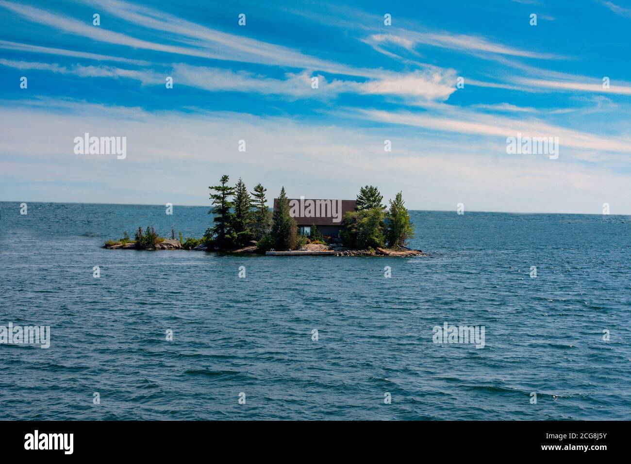 Gebäude auf einer kleinen Insel in einem großen See versteckt Große Bäume und Sträucher Stockfoto