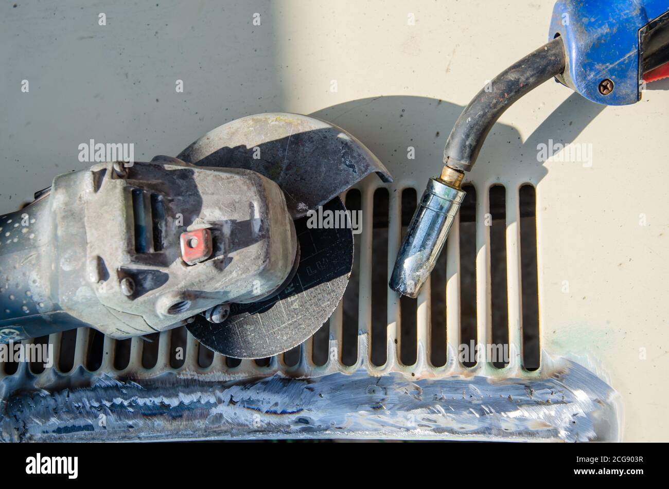 Sägen einer Schweißnaht an Eisenkangeln mit einem Winkelschleifer mit selektivem Fokus auf Funkenflug. Der Prozess der Reinigung und Schleifen einer Metallecke Stockfoto