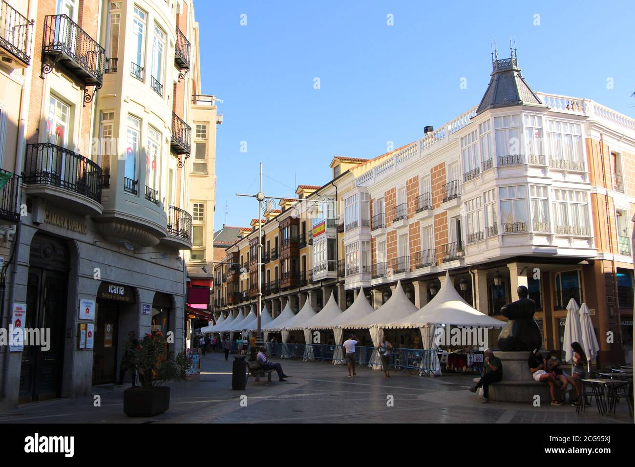 Blick auf die Calle Mayor während der Pandemie mit Markt Stände unter Pavillons Fußgänger und die Mujer Statue Palencia Castile Und Leon Spanien Stockfoto