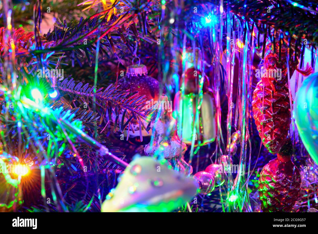 Weihnachtsbaum Urlaub Hintergrund mit Girlande, Glas Spielzeug, Bälle, Lichter. Bunte Dekoration Nahaufnahme in dunklen Schlüssel. Stockfoto