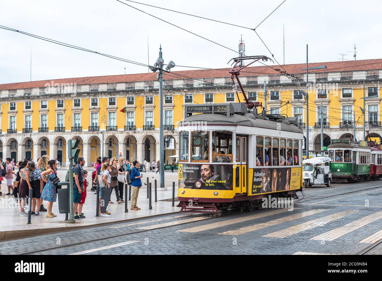 Lissabon, Portugal - 8. Aug 2019: Menschen warten auf die Straßenbahn auf dem Praca do Comercio Platz mit gelben Details Stockfoto