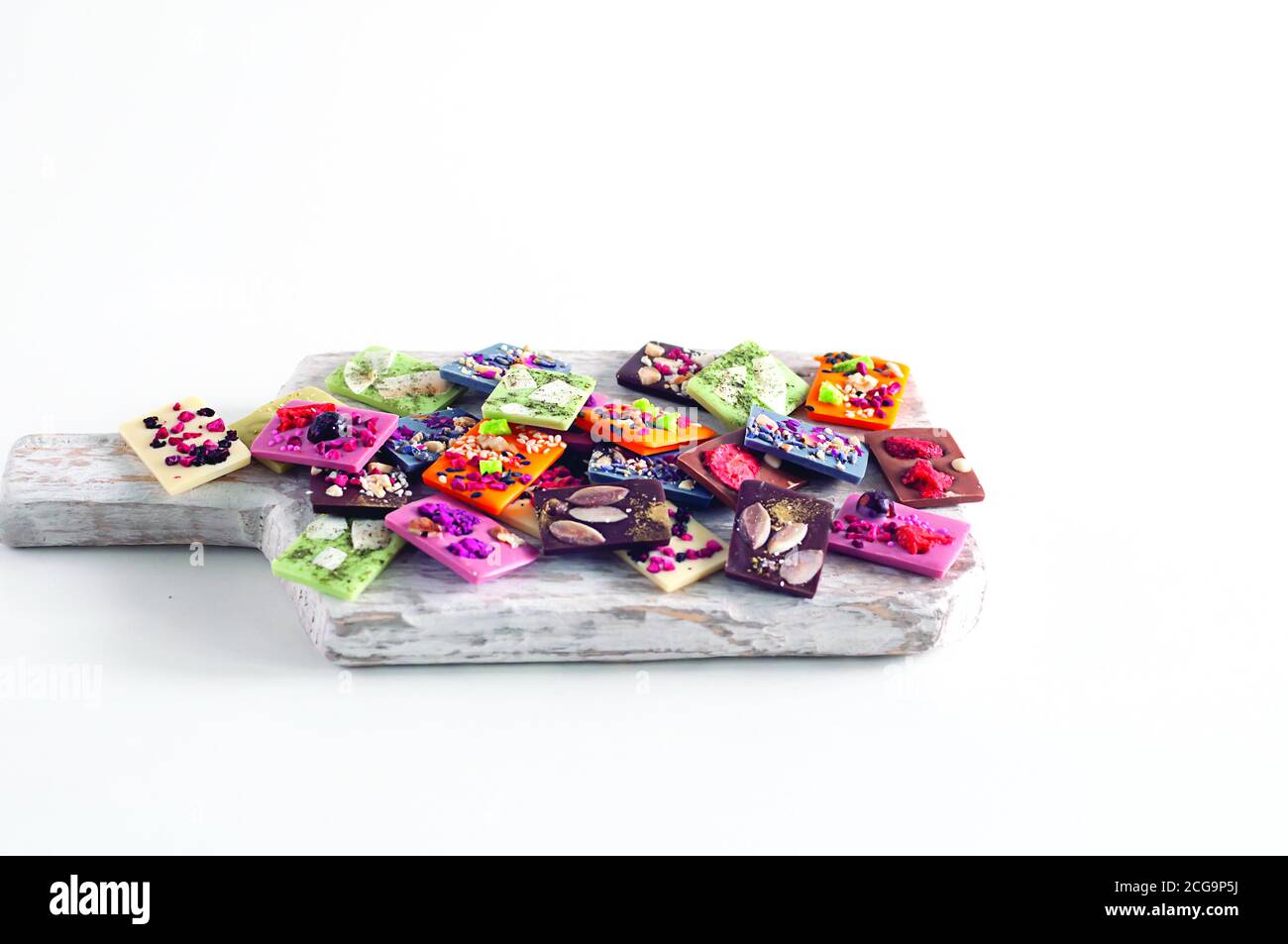 Natürliche belgische Schokolade mit verschiedenen Geschmacksrichtungen, aus Bio-Produkten, Matcha-Tee, grün, blau, Kokosnuss, bestreut mit Fruchtchips, Nüsse, Samen. Stockfoto