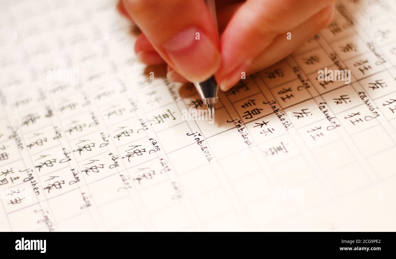 Mädchen schreibt chinesische Hieroglyphen in einem Notizbuch Stockfoto
