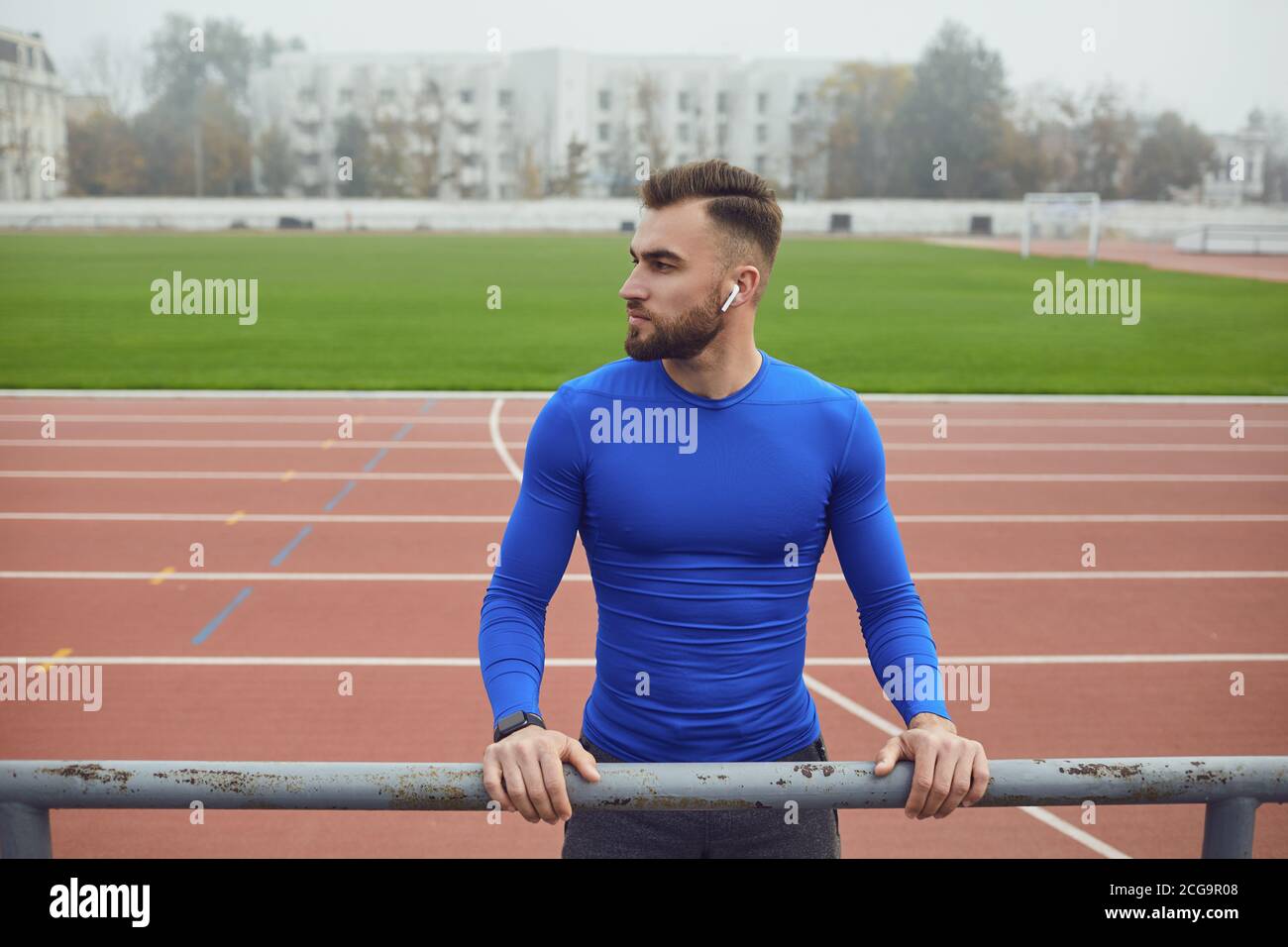 Sport Kerl in blauer Kleidung lächelt, während im Stadion im Nebel auf der Suche Stockfoto