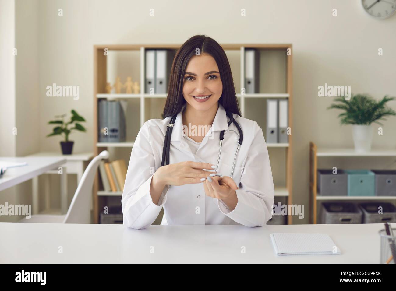 Ärztin beim Betrachen der Kamera und beim Sprechen während einer Online-Konsultation. Stockfoto