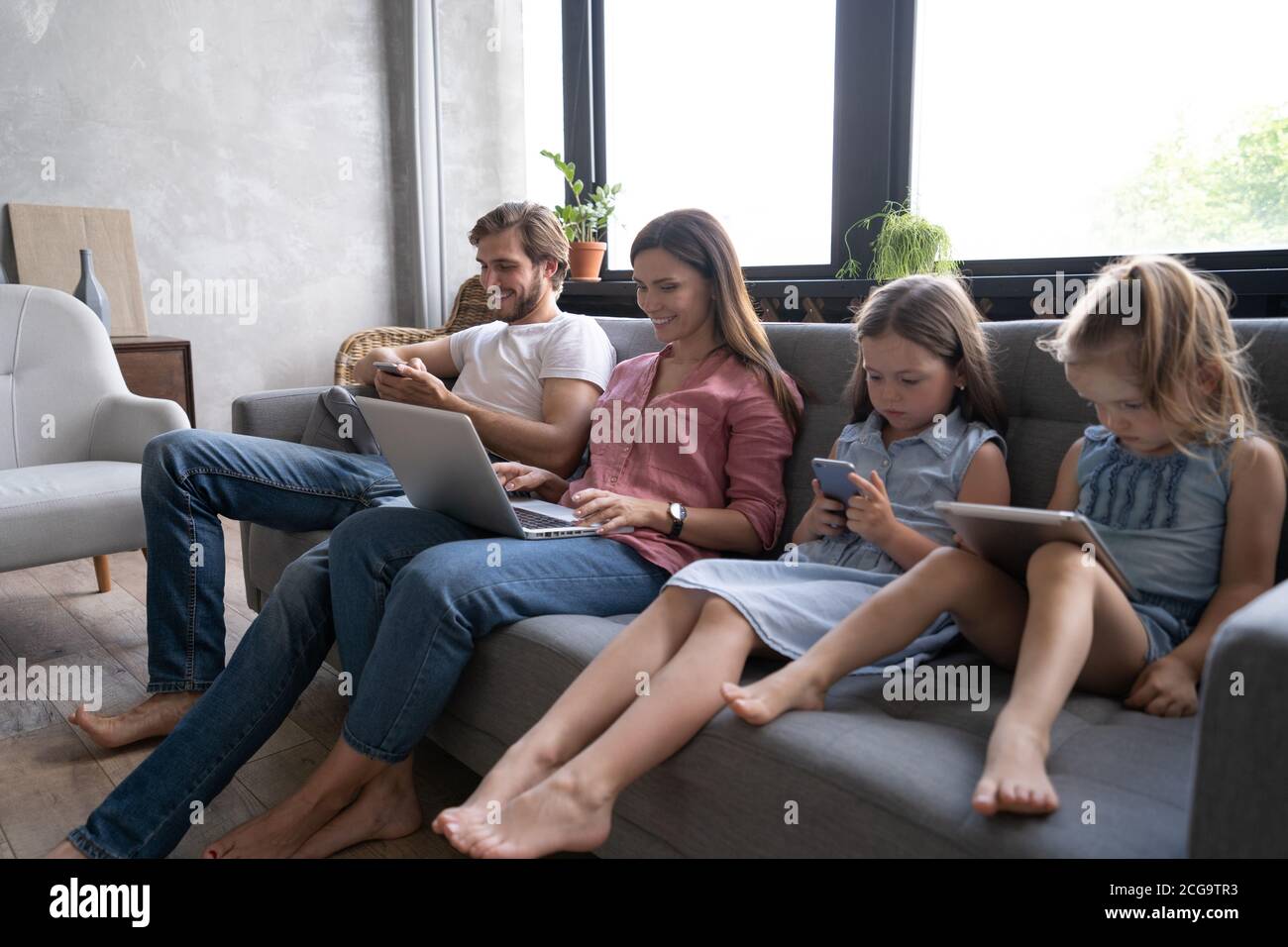 Moderne Familienwerte. Vater, Mutter und Töchter mit elektronischen Geräten Stockfoto