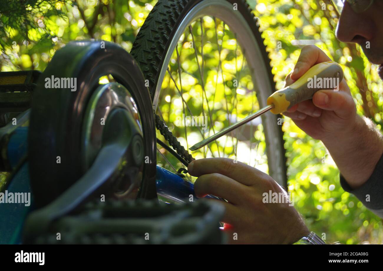Die Pflege des Fahrrads im Freien. Reparatur der Kette auf einem Zahnrad auf einem Fahrrad. Stockfoto