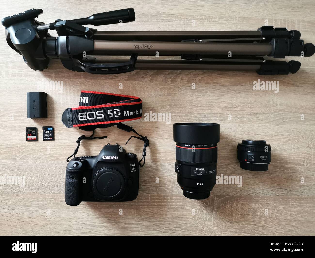 Set der Kamera und Fotoausrüstung: Zwei Objektive, Körper Canon 5d Mark iv, zwei Speicherkarte, Akku und Stativ auf Holztisch Stockfoto