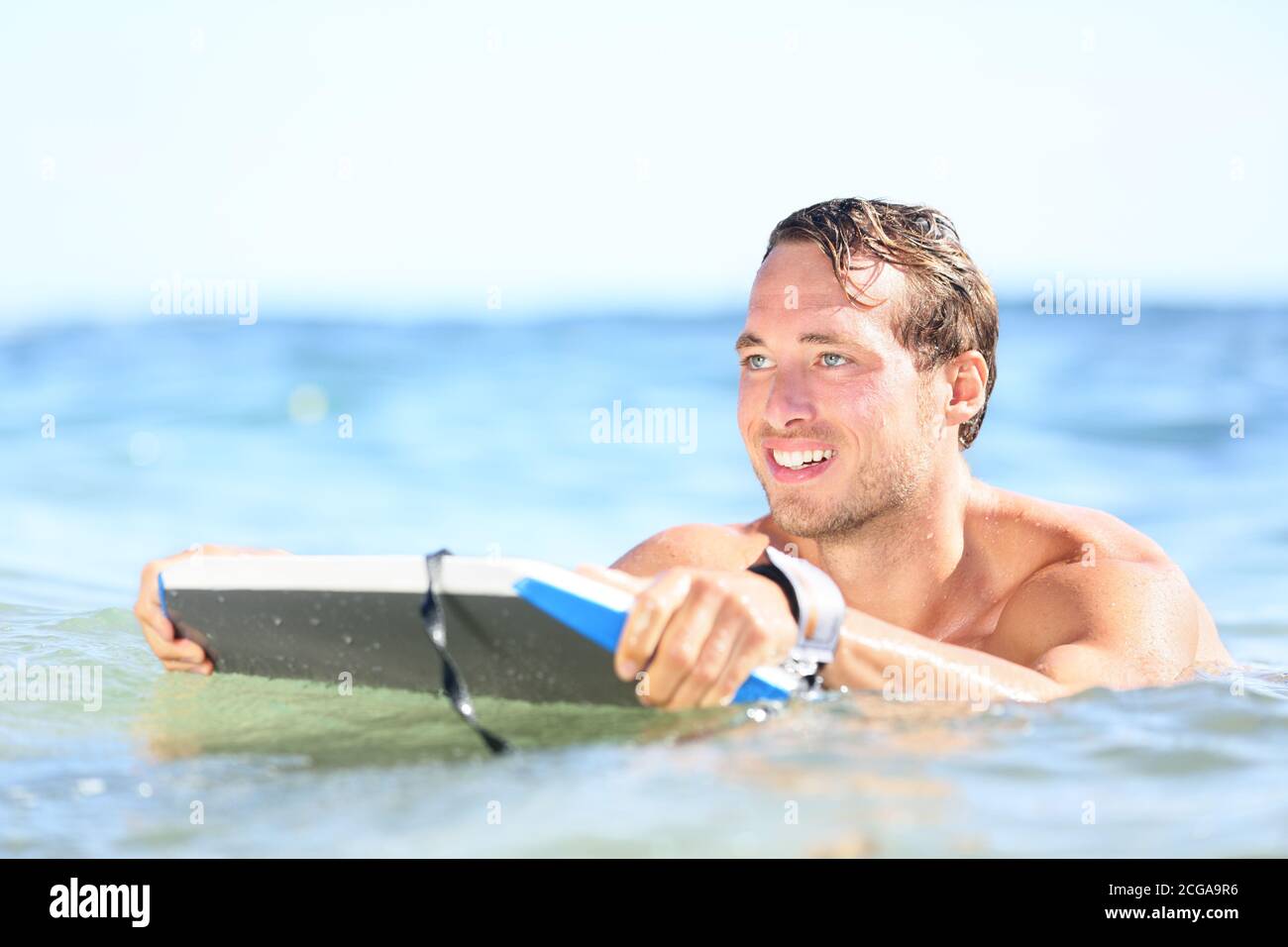 Strandmann mit Spaß im Wasser lächelt glücklich. Porträt von jungen schönen männlichen Strand Modell Surfen auf Bodyboard Stockfoto