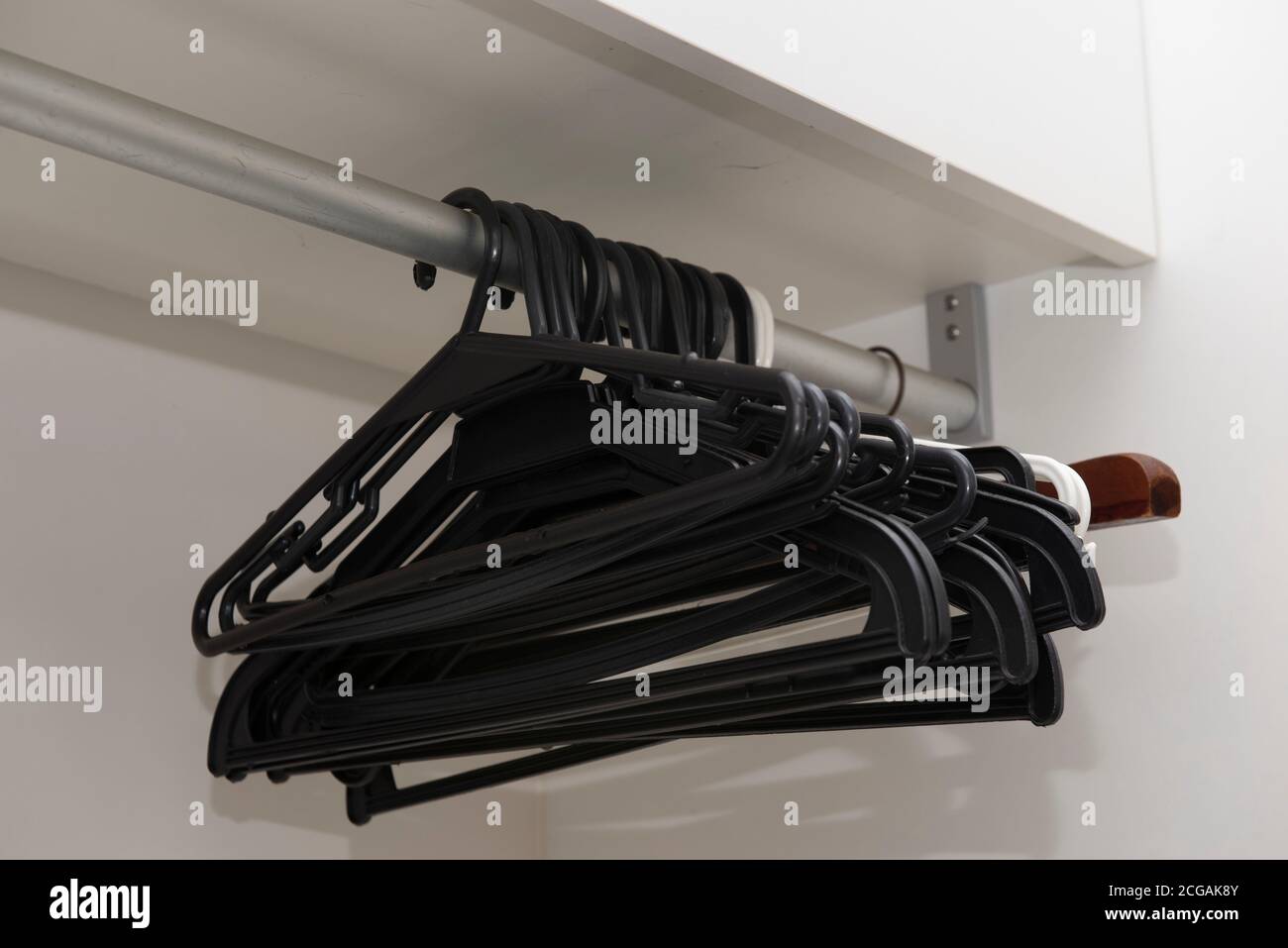 Eine Gruppe leerer Kleiderbügel, die an einer Edelstahlstange hängen. Leeres Schrankkonzept ohne Kleidung. Stockfoto