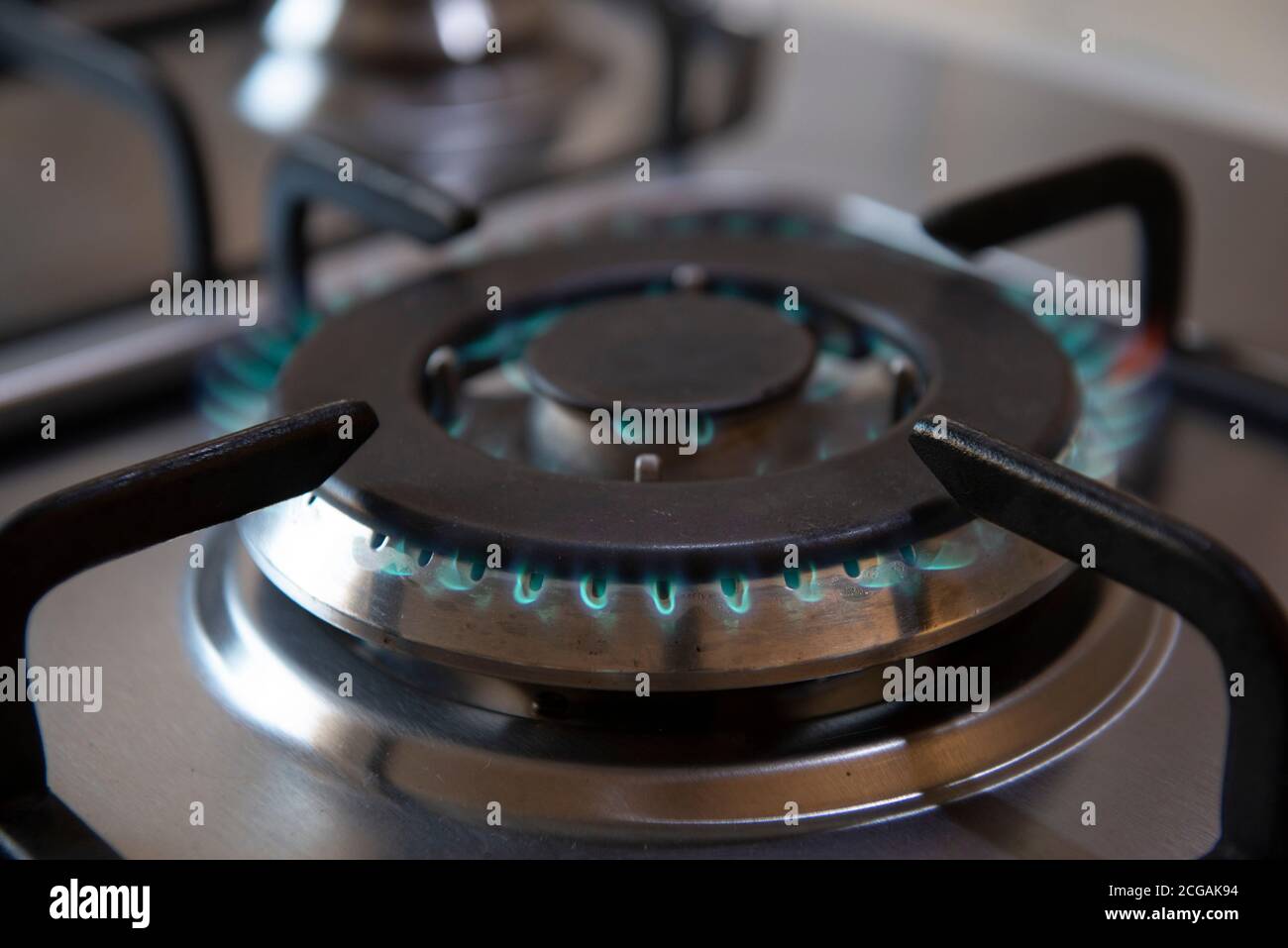 Küche Gasherd mit brennendem Feuer Propangas. Gasflamme eines Gasherd aus Edelstahl. Gasflamme eines Gasofens. Nahaufnahme eines Gasbrenners auf einem Stockfoto