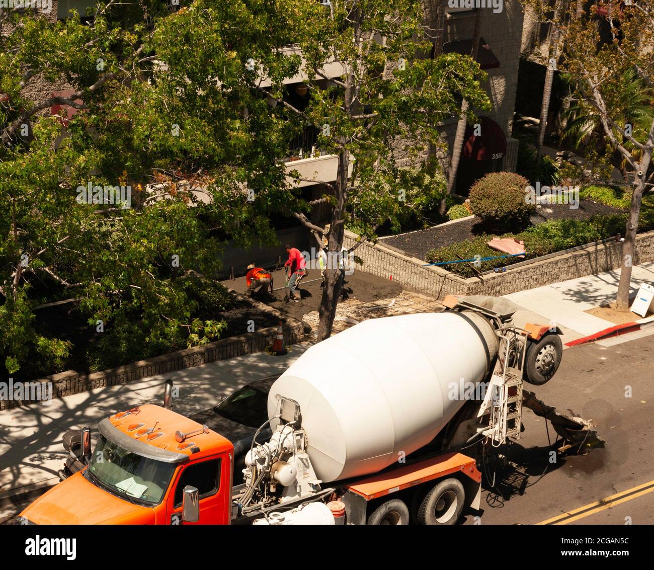 Zementmischer LKW und Arbeiter Beton für die Auffahrt zu legen. Overhead-Ansicht von LKW, Arbeiter, Stadtstraße und Wohngebäude in San Diego, Kalifornien. Stockfoto