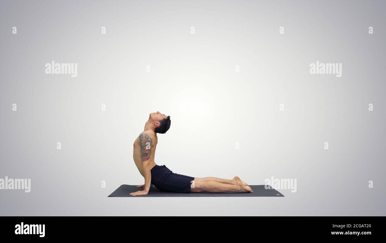 Flexible starke yoga Mann in Nach oben und Nach unten schauenden Hund Urdhva Mukha Svanasana auf Farbübergang Hintergrund. Stockfoto