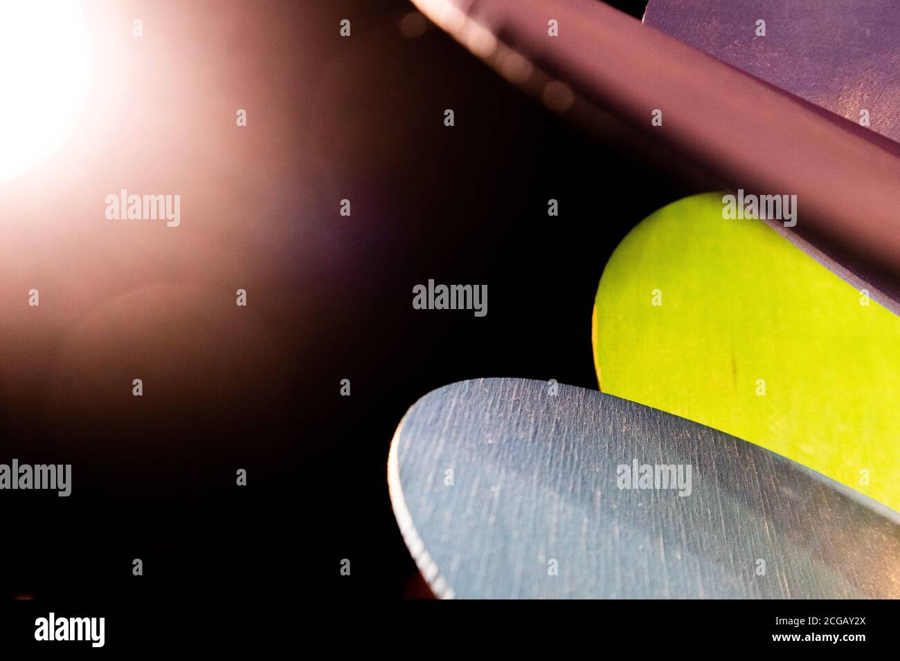 Nahaufnahme von abstrakten und farbenfrohen blauen, grünen und violetten Formen in der Dunkelheit mit hellem Licht in der Ecke Stockfoto
