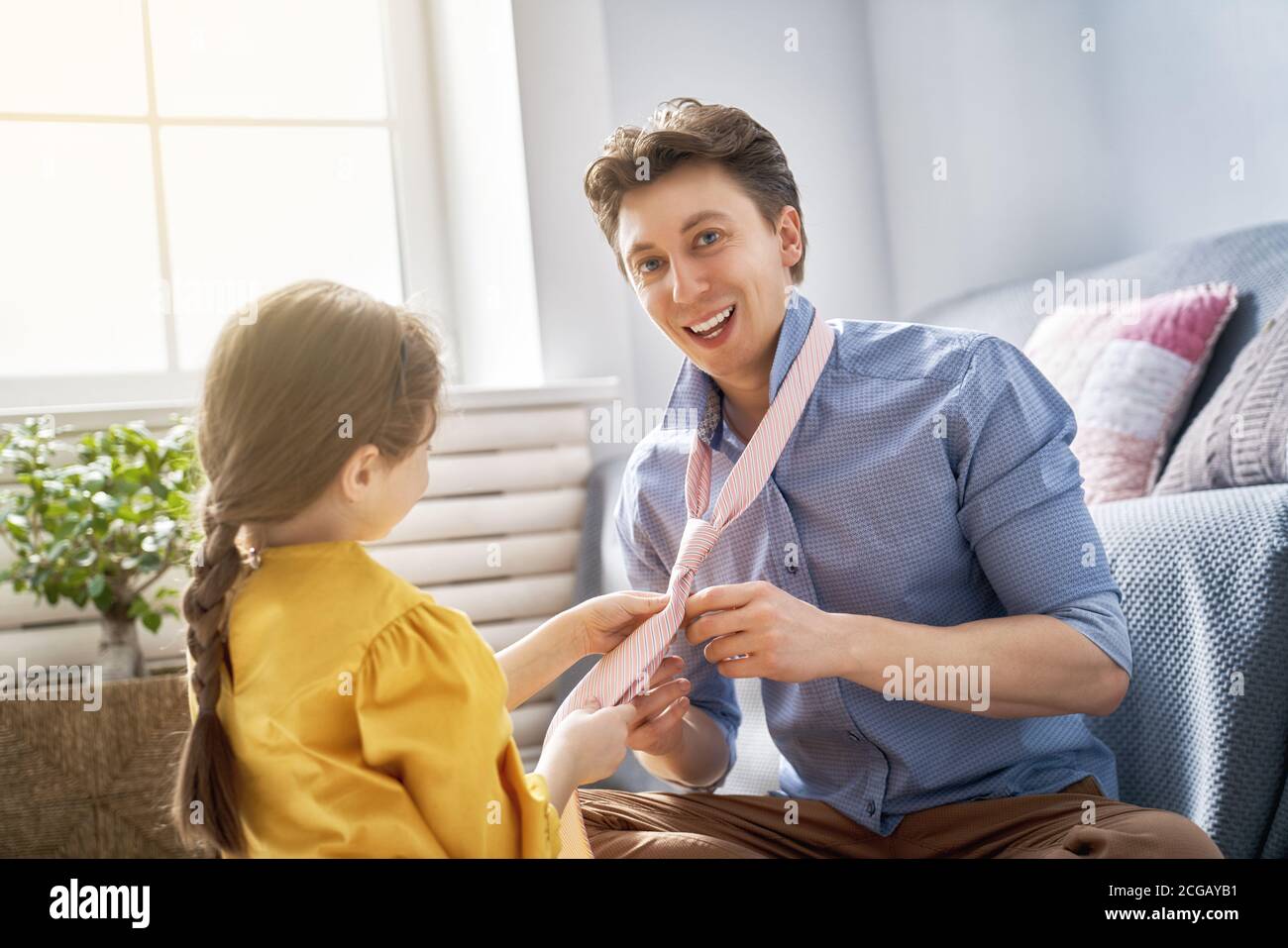 Alles gute zum Vatertag! Papa und seine Tochter spielen zu Hause. Das Mädchen, das die Krawatte für ihren Papa bindet. Familienurlaub und Zweisamkeit. Stockfoto