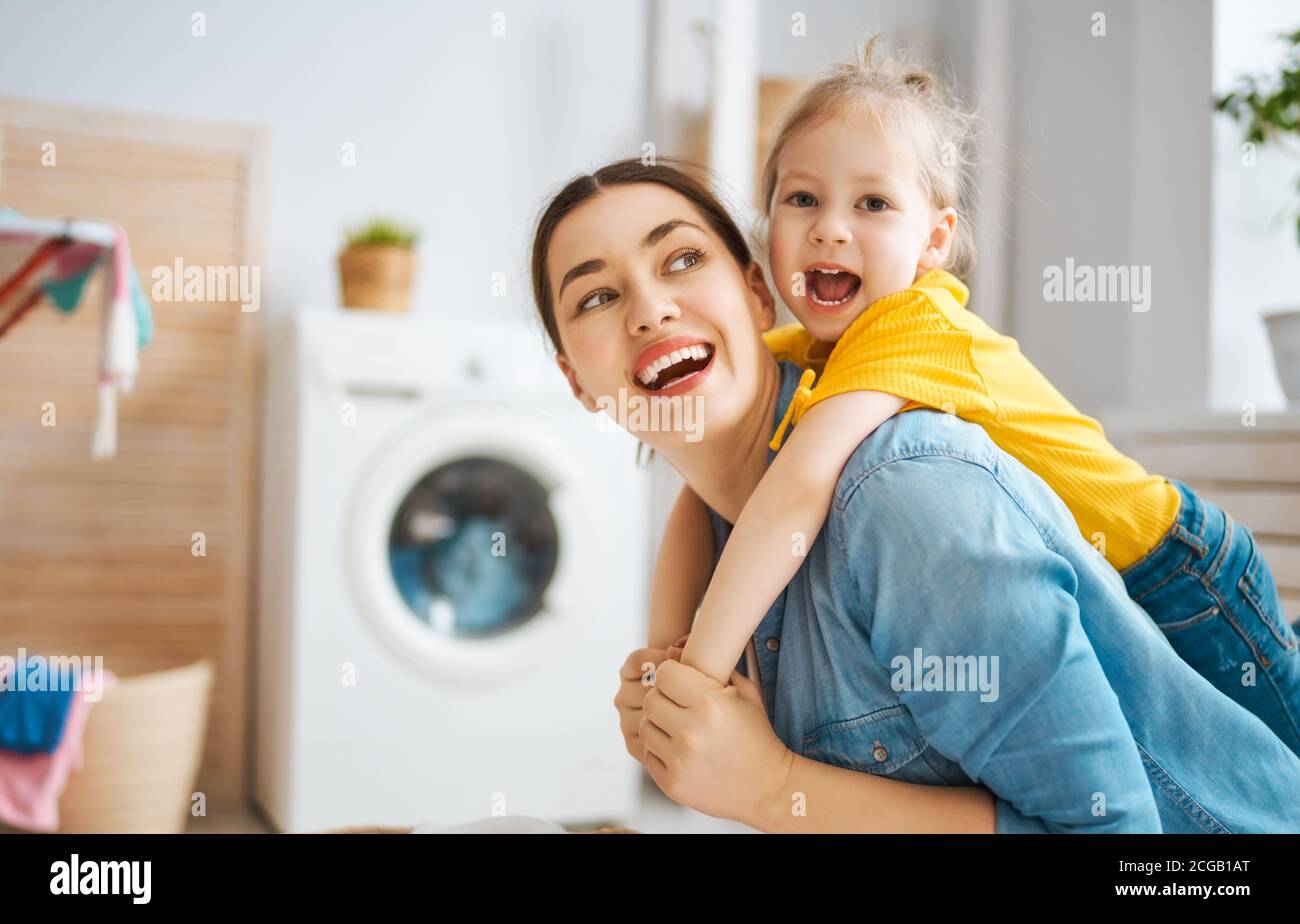 Schöne junge Frau und Kind Mädchen kleinen Helfer haben Spaß und Lächeln, während die Wäsche zu Hause. Stockfoto