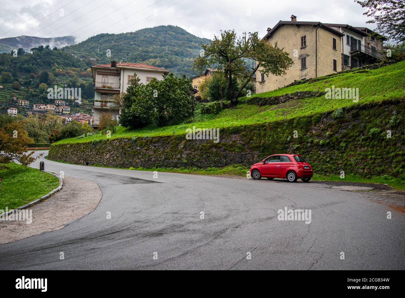 Kleines rotes Auto auf der Straße eine kleine Stadt am Comer See, die in Norditalien liegt. Reisekonzept. Stockfoto