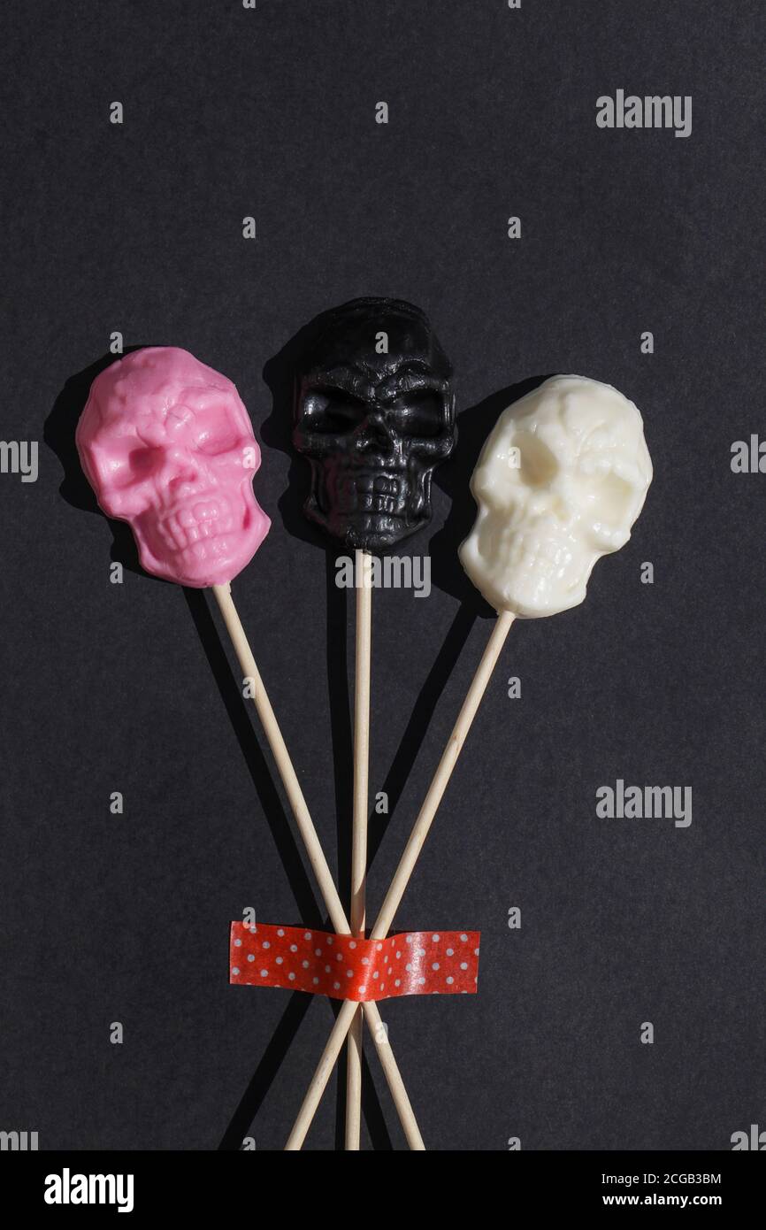 Lutscher in Form von Schädel auf schwarzem Hintergrund. Kreative Halloween Minimal Konzept. Flach legen Draufsicht Kopieplatz Stockfoto