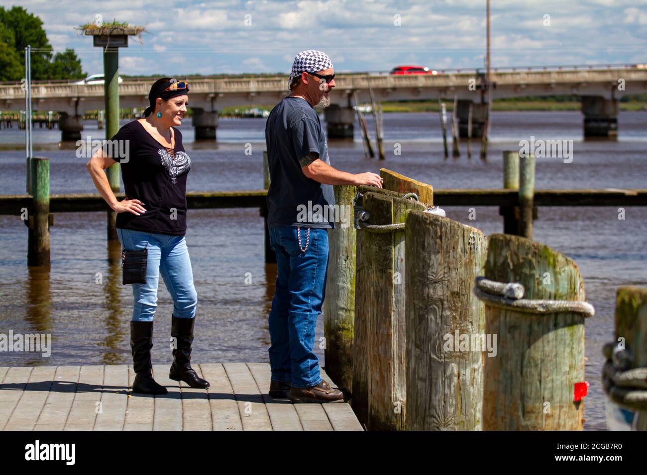 Chestertown, MD, USA, 08/30/2020: Ein Rocker mittleren Alters steht auf dem Dock am Chester River. Beide tragen Bandanna, Sonnenbrille, Jeans und le Stockfoto