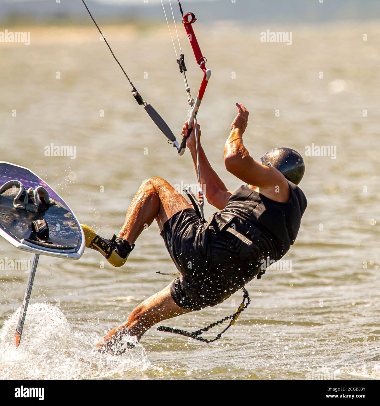Ein Kitesurfer mit Schutzausrüstung verliert das Gleichgewicht und fällt vom Brett ins Meer vor der Küste von Assateague Island. Ein großes Wasser spl Stockfoto