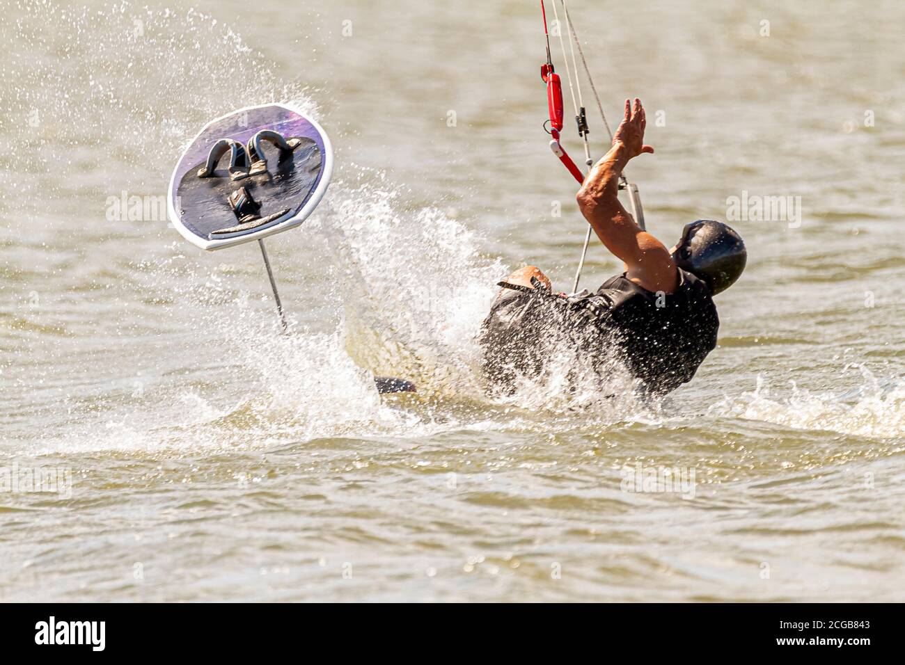Ein Kitesurfer mit Schutzausrüstung verliert das Gleichgewicht und fällt vom Brett ins Meer vor der Küste von Assateague Island. Ein großes Wasser spl Stockfoto