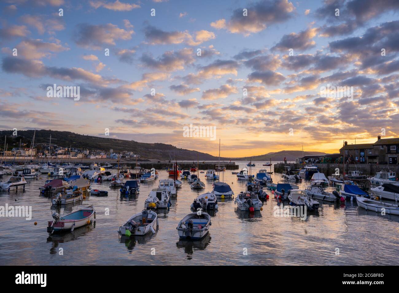 Lyme Regis, Dorset, Großbritannien. September 2020. Wetter in Großbritannien: Boote, die im Hafen von Cobb festgemacht sind, leuchten an einem kühlen Morgen im Küstenresort Lyme Regis unter einem wunderschönen herbstlichen Sonnenaufgang auf, wenn der Hochdruck in die Region übergeht und trockene und besiedelte Bedingungen vor einer vorhergesagten Mini-Hitzewelle bringt. Kredit: Celia McMahon/Alamy Live Nachrichten Stockfoto