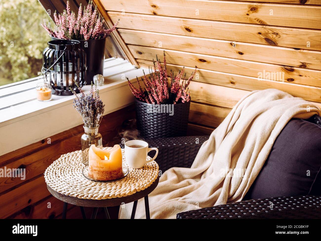 Niedliche Herbst Hygge Home Dekor Anordnung. Winziger Holzbalkon mit Heideblumen, Lavendel in Flaschenvase, Kerzenlicht Flamme, weiches beiges Karabinett Stockfoto