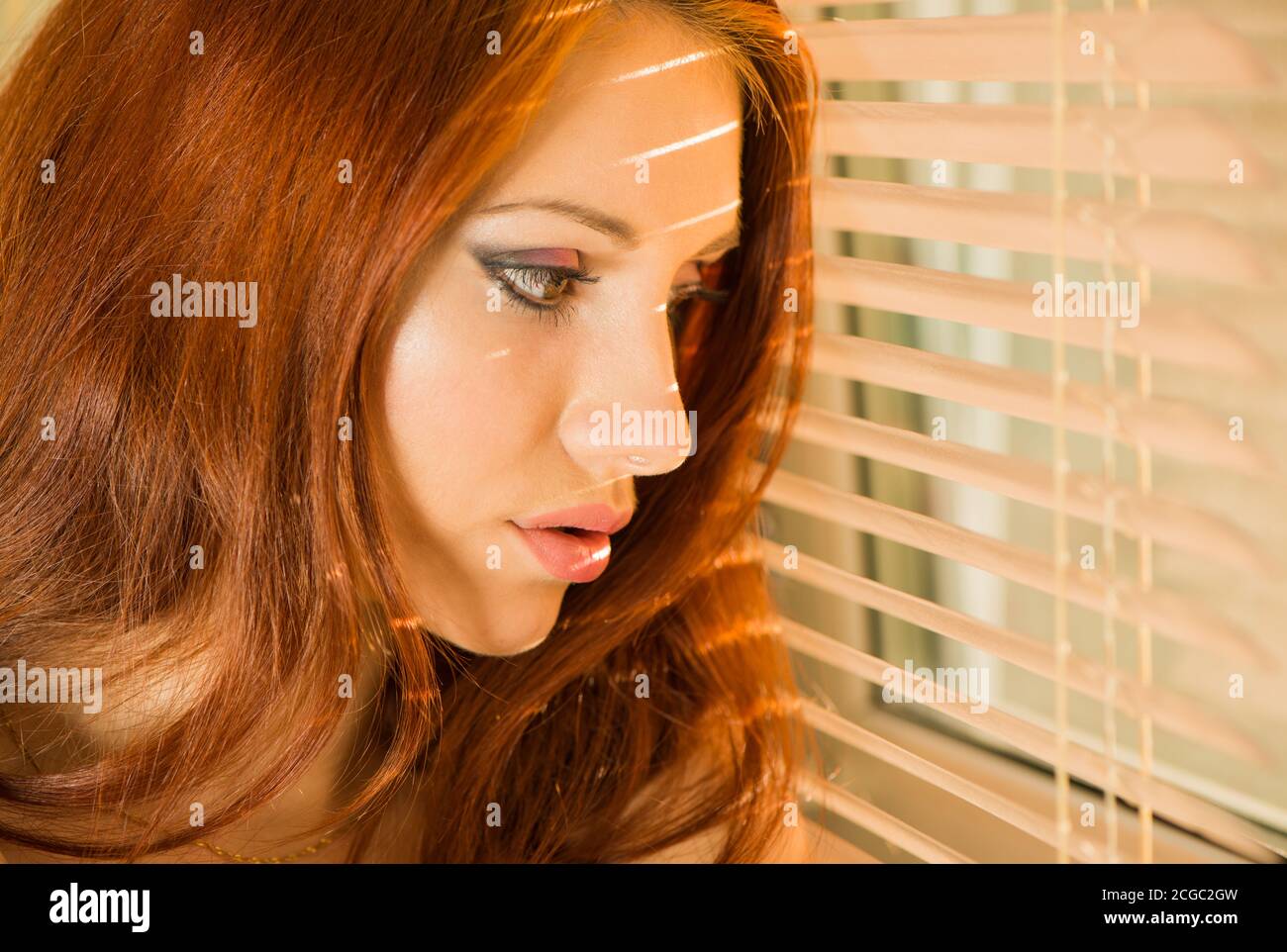 Junge hübsche Frau Nahaufnahme Porträt innen an Fensterläden Stockfoto