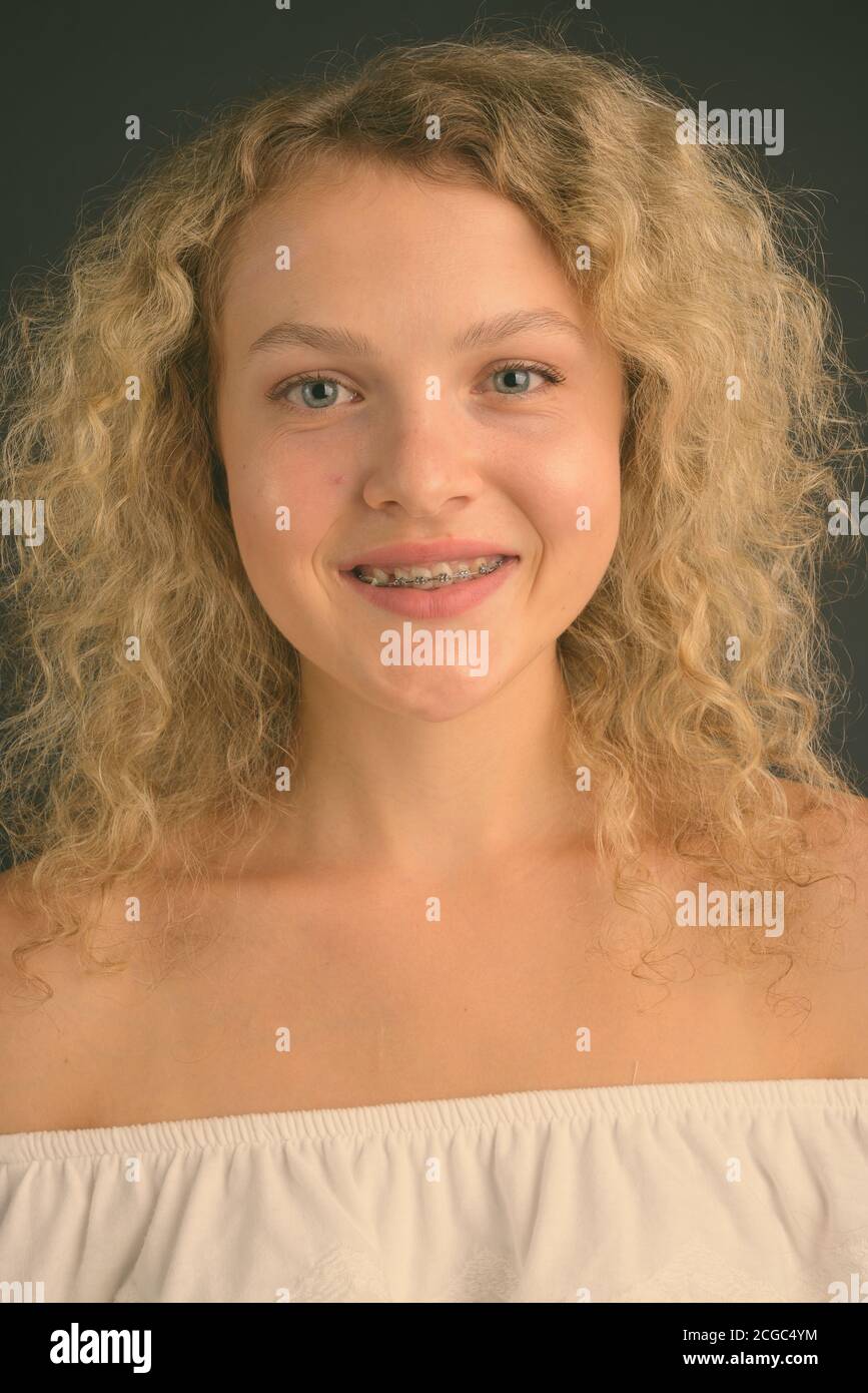 Junge schöne Frau mit blondem lockiges Haar vor grauem Hintergrund Stockfoto