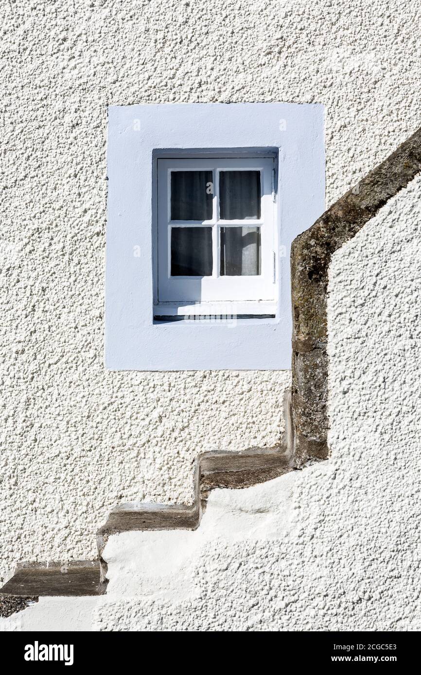 Kleines Fenster mit blassblauer Umrandung und Steintreppen. Stockfoto