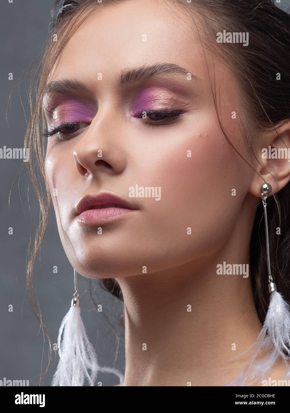 Stilvolle und elegante Braut in einem modernen Anzug, Porträt. Make-up in rosa Farbtönen, Ohrhänger mit weißen Federn. Stockfoto