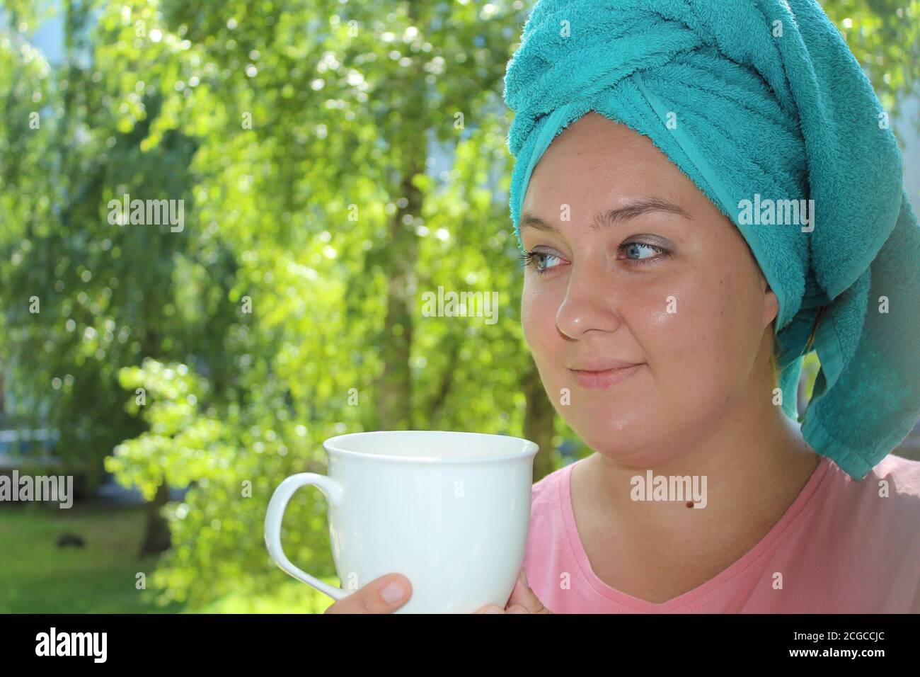Junge Frau trinkt Kaffee auf dem Balkon auf dem Hintergrund der Natur. Glückliche Frau am Morgen Stockfoto