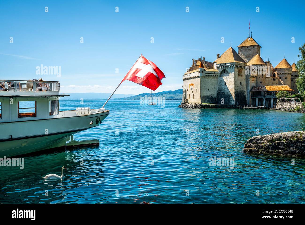 Schweizer Flagge auf der Rückseite eines Bootes und Chillon Schloss mit sonnigem blauen Himmel in der Waadtländer Schweiz Stockfoto